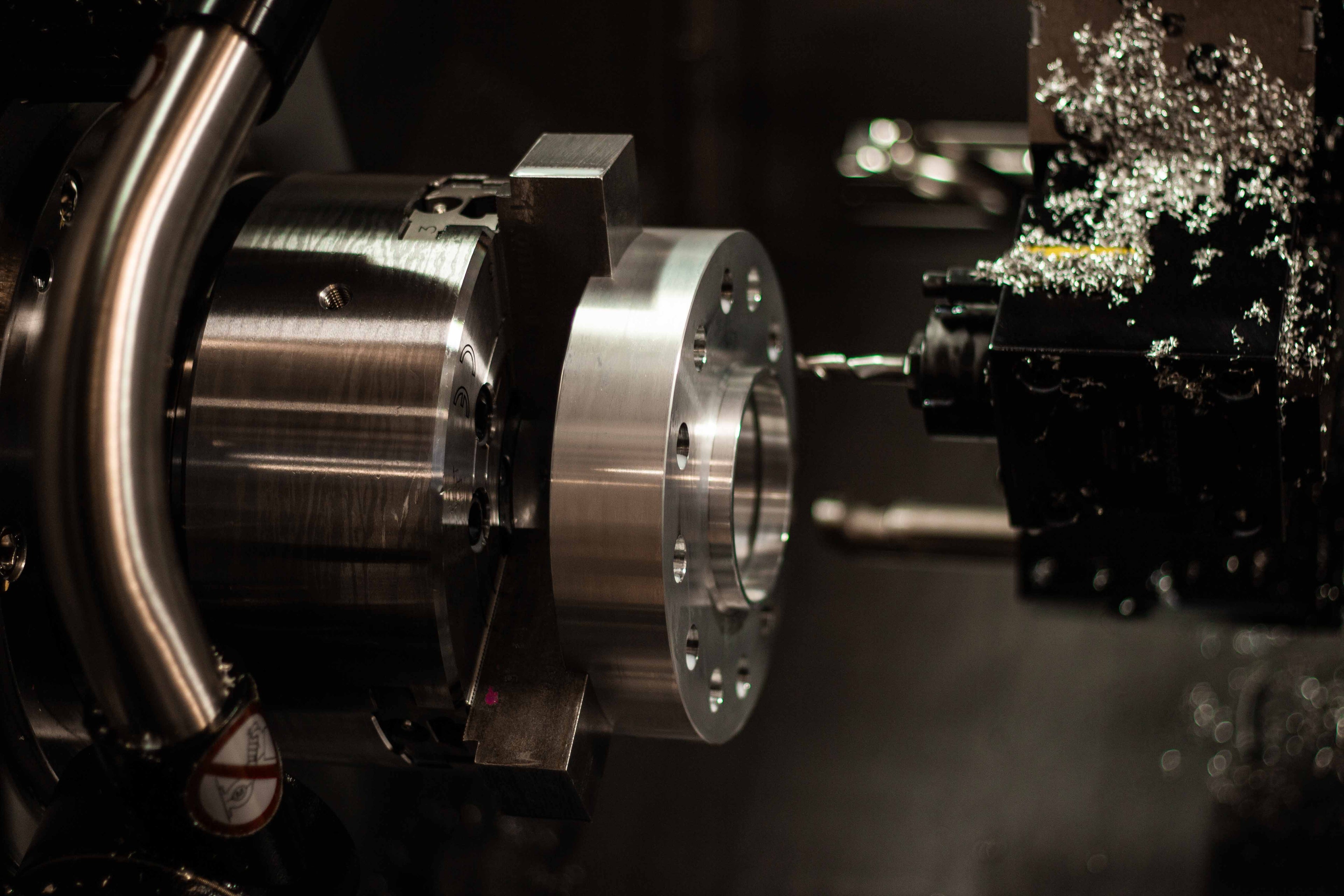 Close-up photo of a partially machined billet aluminum wheel spacer in the chuck of a CNC machine at BSB USA.