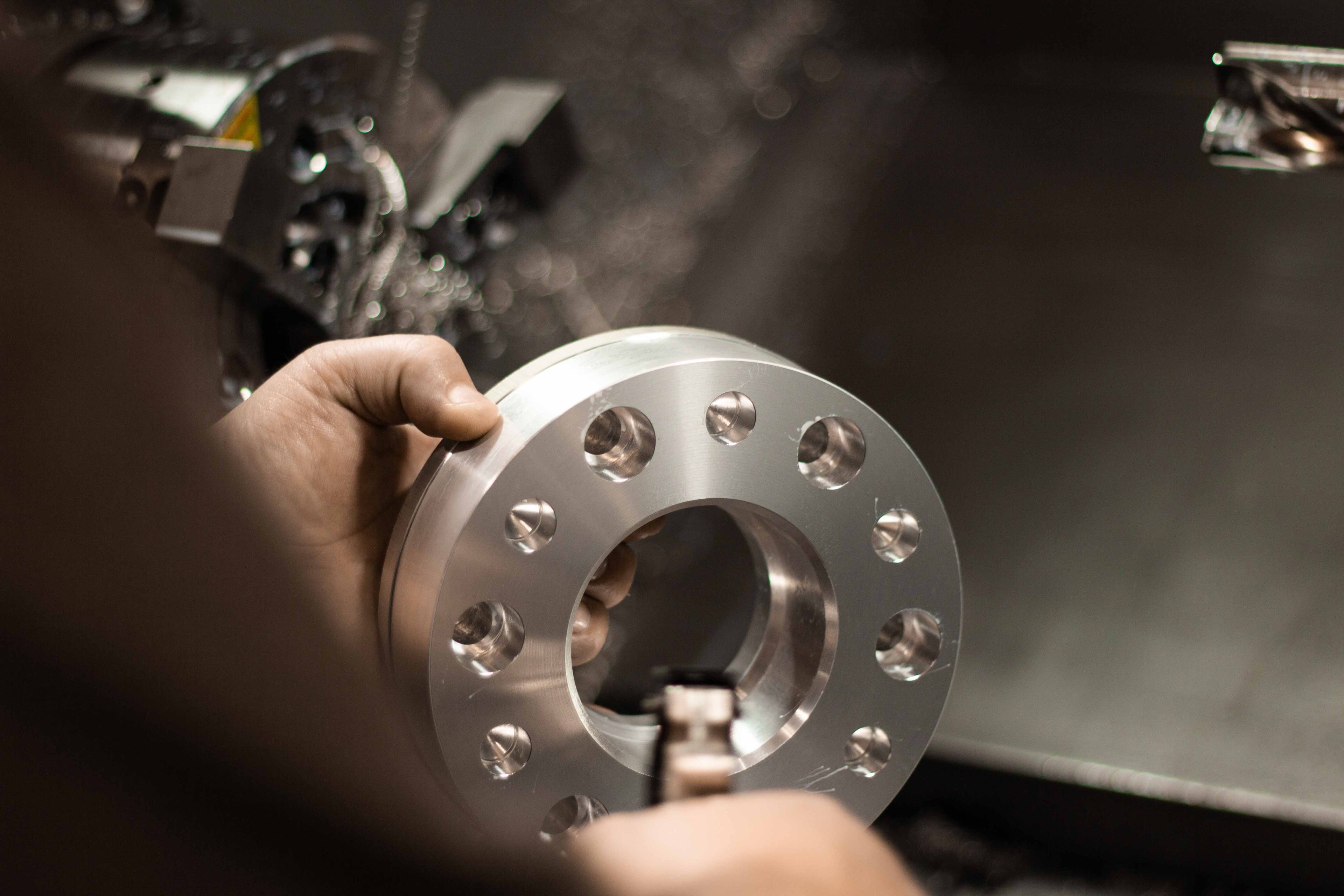 Photo of a machinist blowing off a partially machined billet aluminum wheel spacer after the first CNC process at BSB USA.