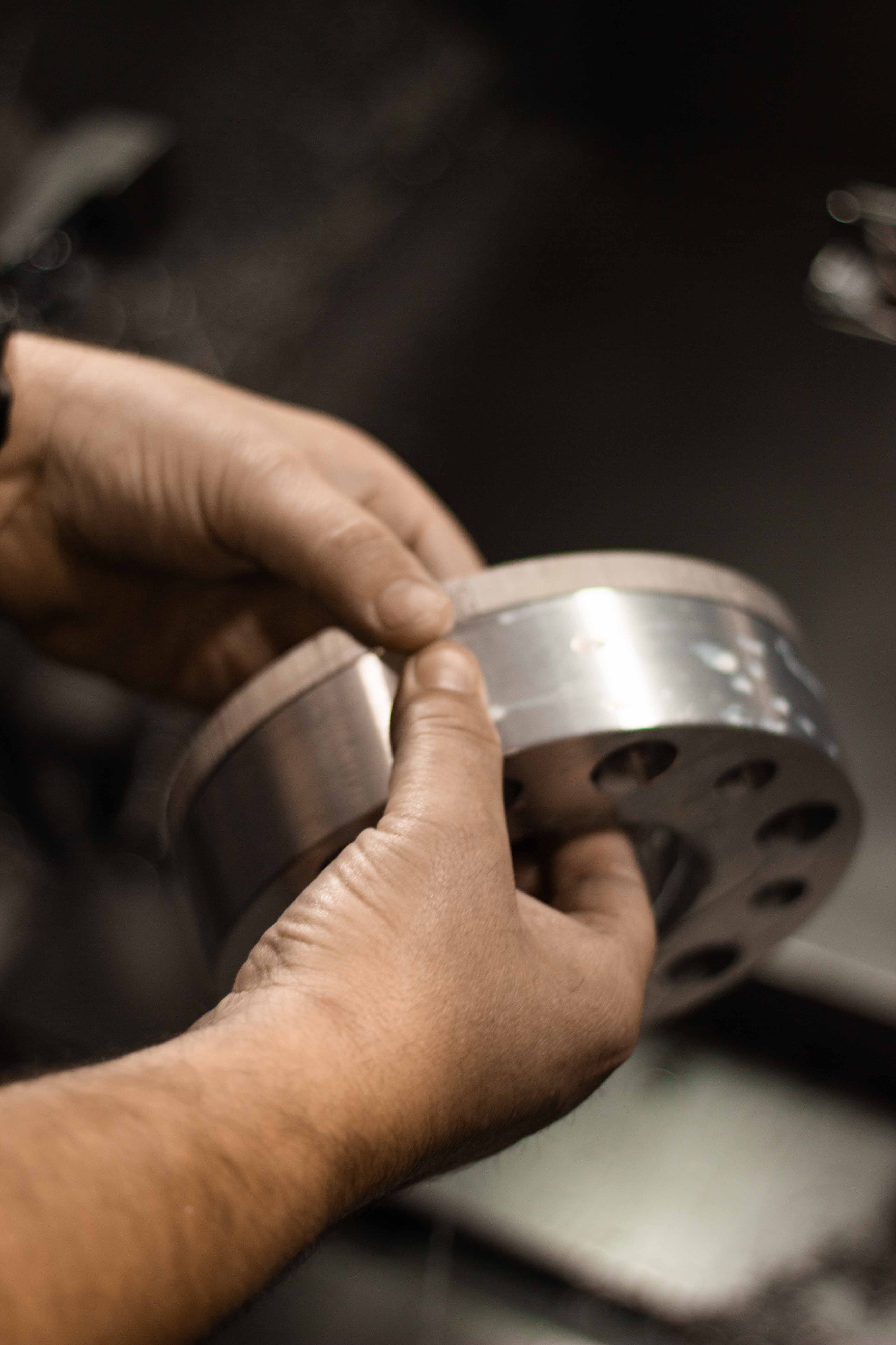 Machinist handling a partially machined billet aluminum wheel spacer during the CNC process at BSB USA.