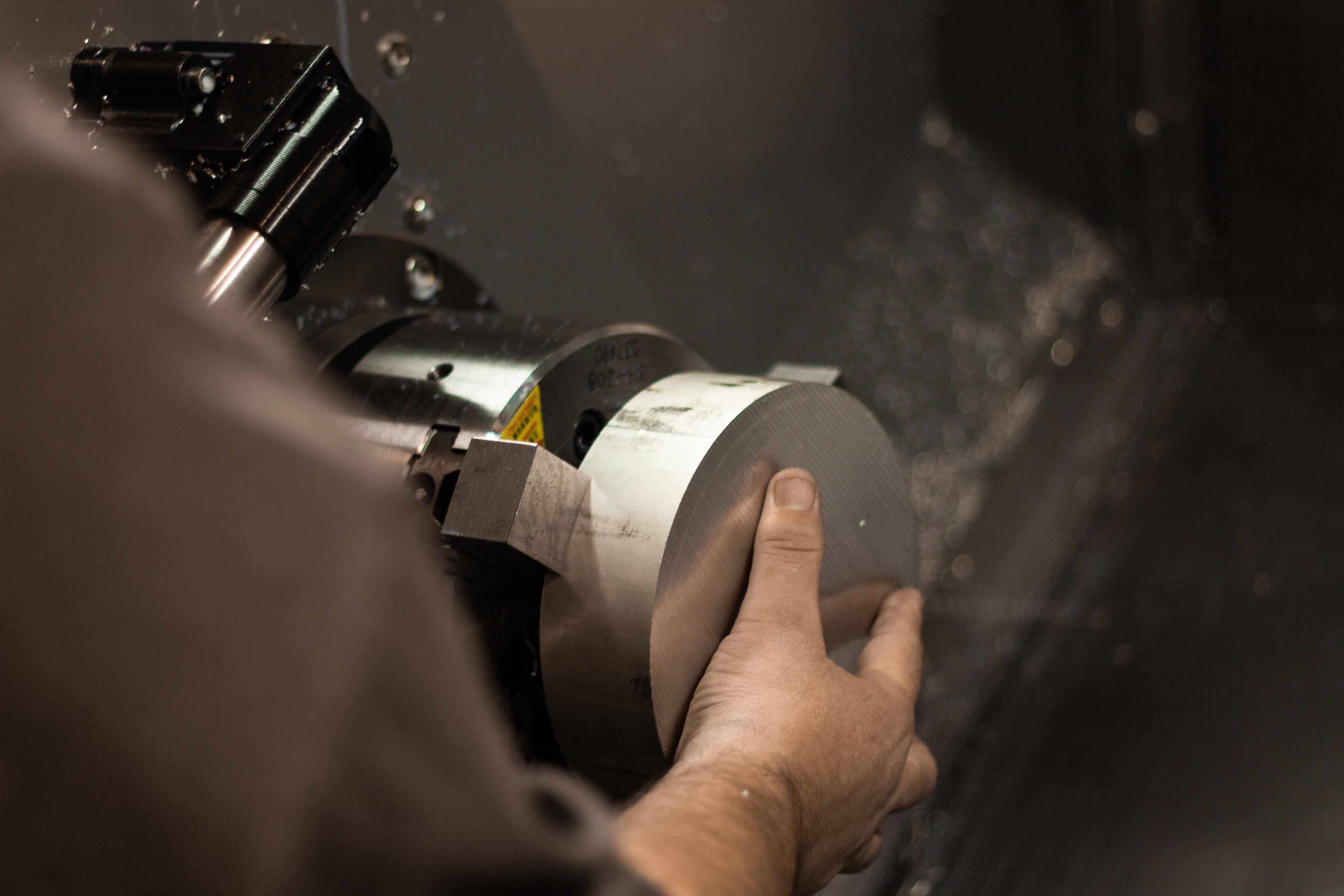 Close-up of a machinist loading a raw billet of aluminum into the chuck of a CNC machine to machine BSB USA wheel spacers.