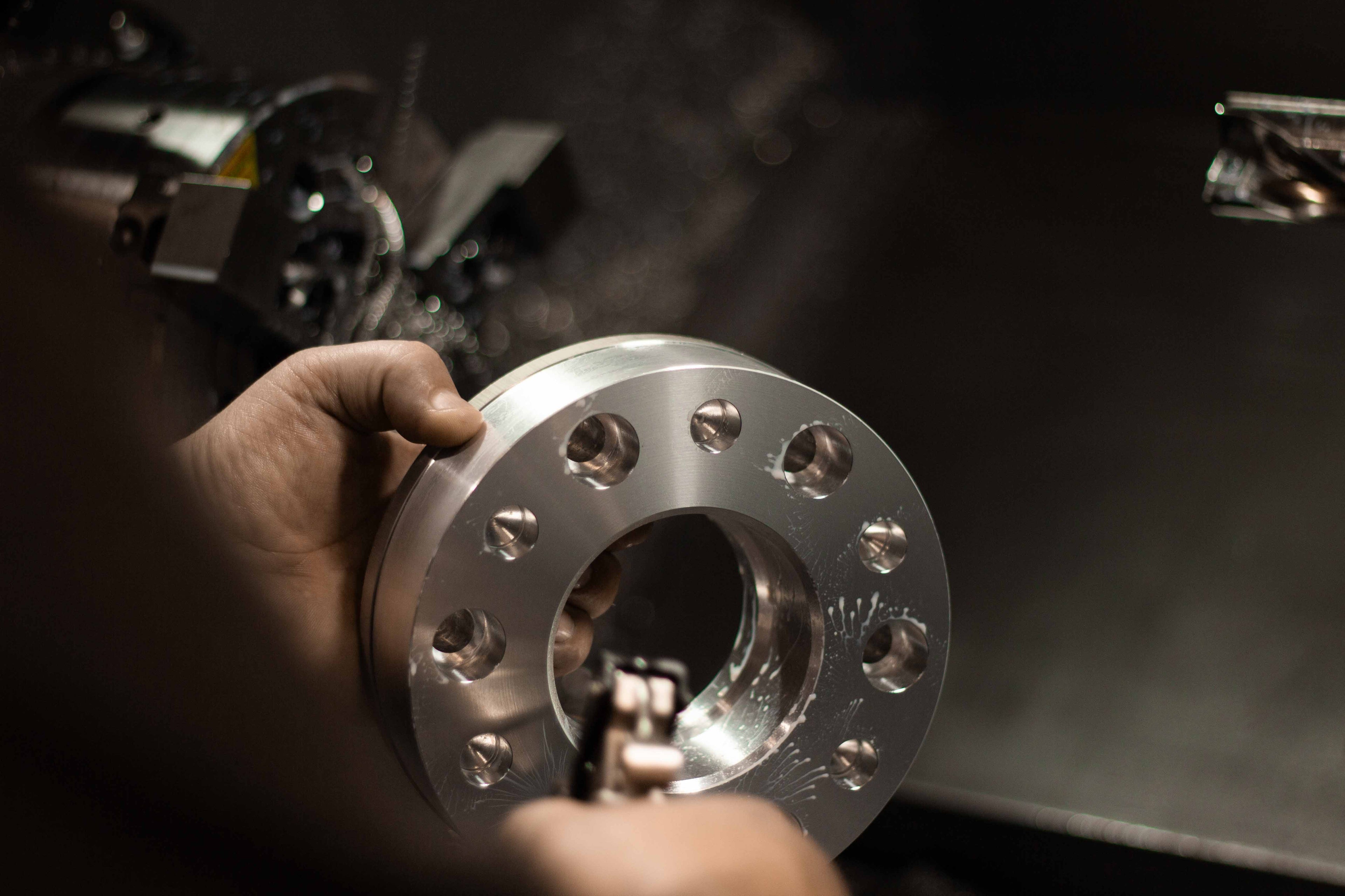 Machinist blowing off wheel spacer after first CNC machining process.