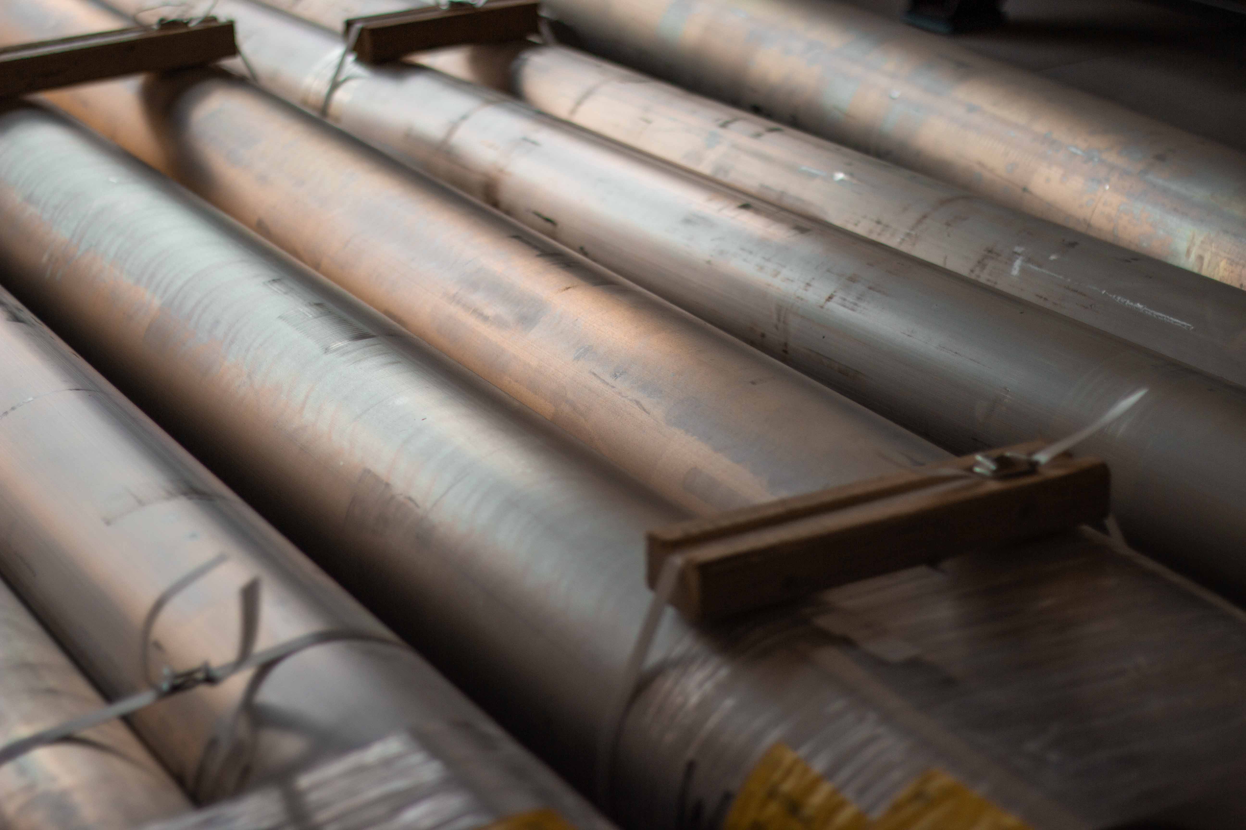 Photo showing multiple bars of raw billet aluminum material in stock at BSB USA before machining.