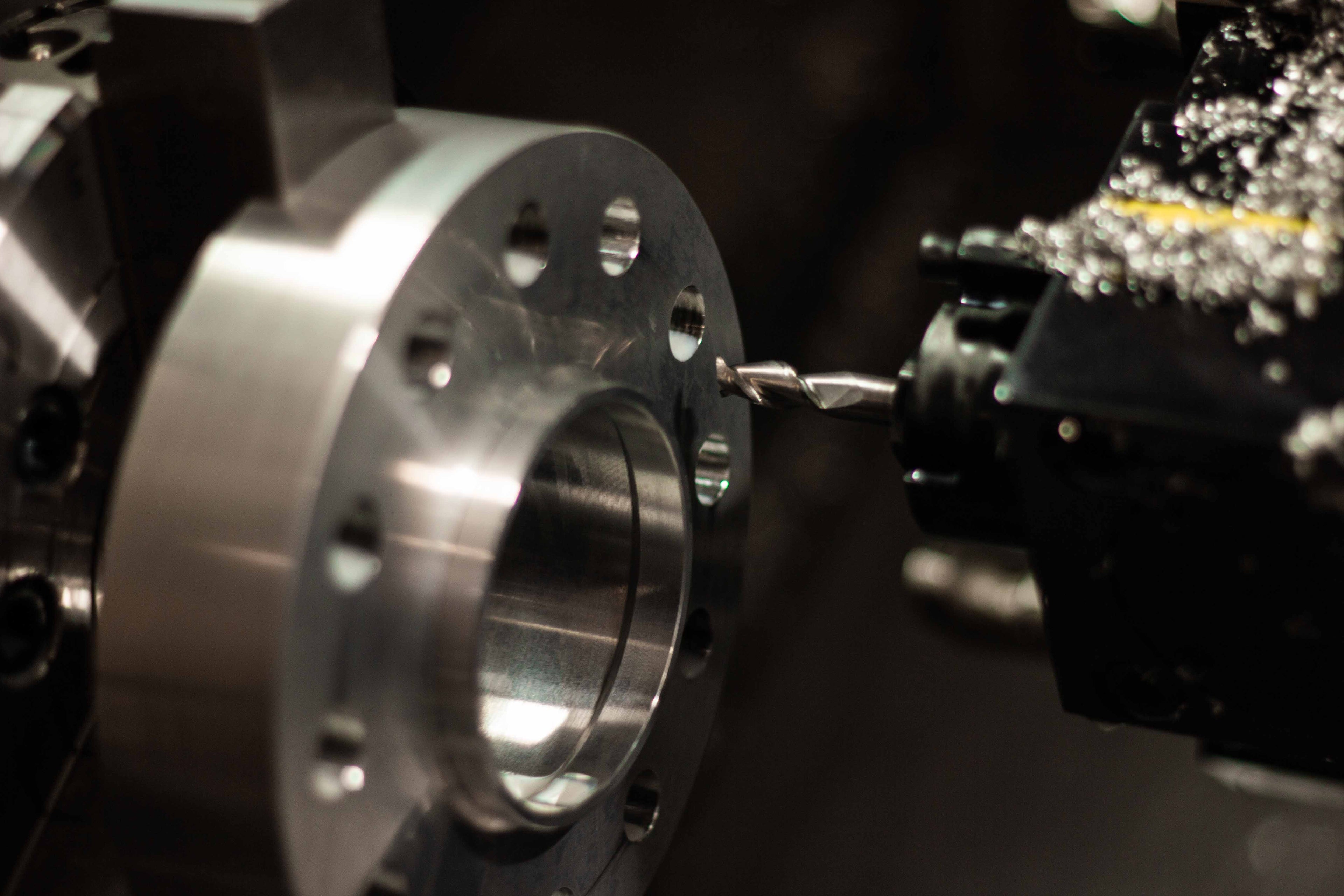 Close-up of a partially machined billet aluminum wheel spacer in the chuck of a CNC machine with the cutting tool visible at BSB USA.